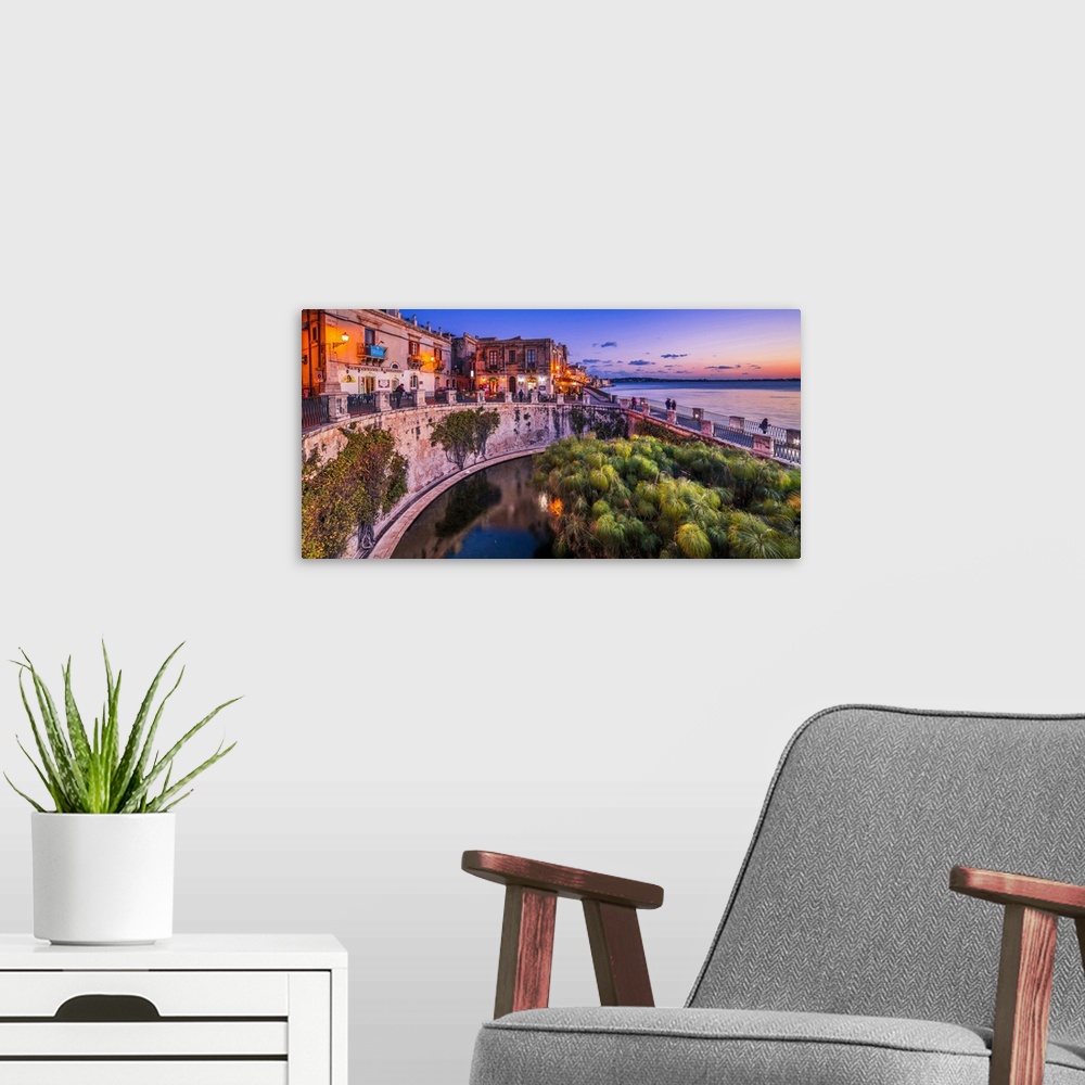 A modern room featuring Italy, Sicily, Siracusa district, Siracusa, Ortigia, Alfeo seafront at dusk, Fonte Aretusa.