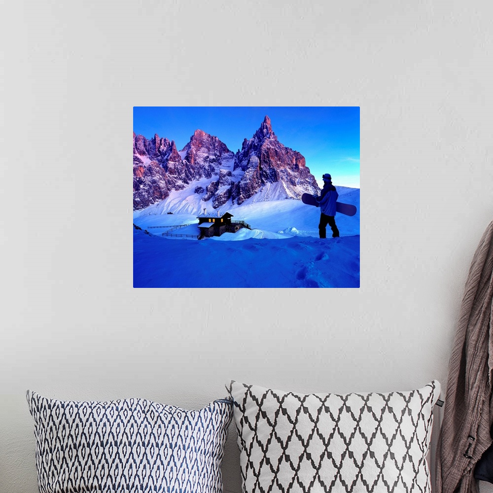 A bohemian room featuring Man holding snowboard while looking at ski resort and mountains