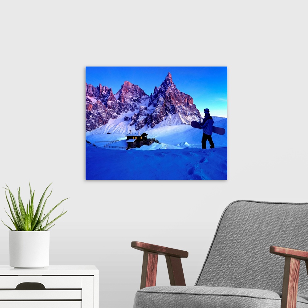 A modern room featuring Man holding snowboard while looking at ski resort and mountains