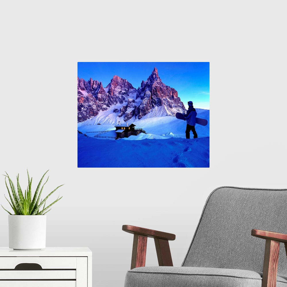 A modern room featuring Man holding snowboard while looking at ski resort and mountains
