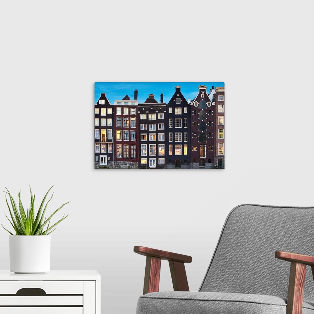 A modern room featuring Netherlands, North Holland, Amsterdam, Typical Dutch houses along the Damrak Canal.