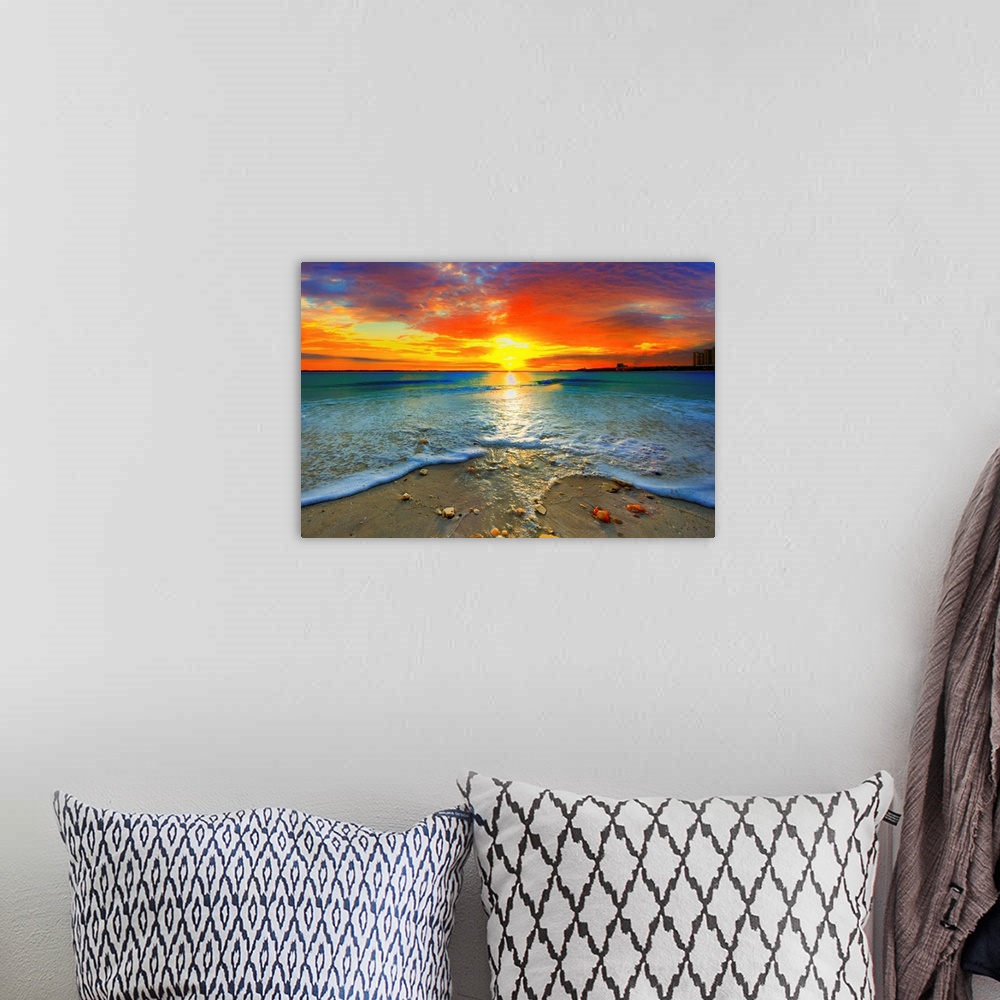 A bohemian room featuring A dark red ocean sunset at seashore. Gentle blue ocean waves roll over the shore.