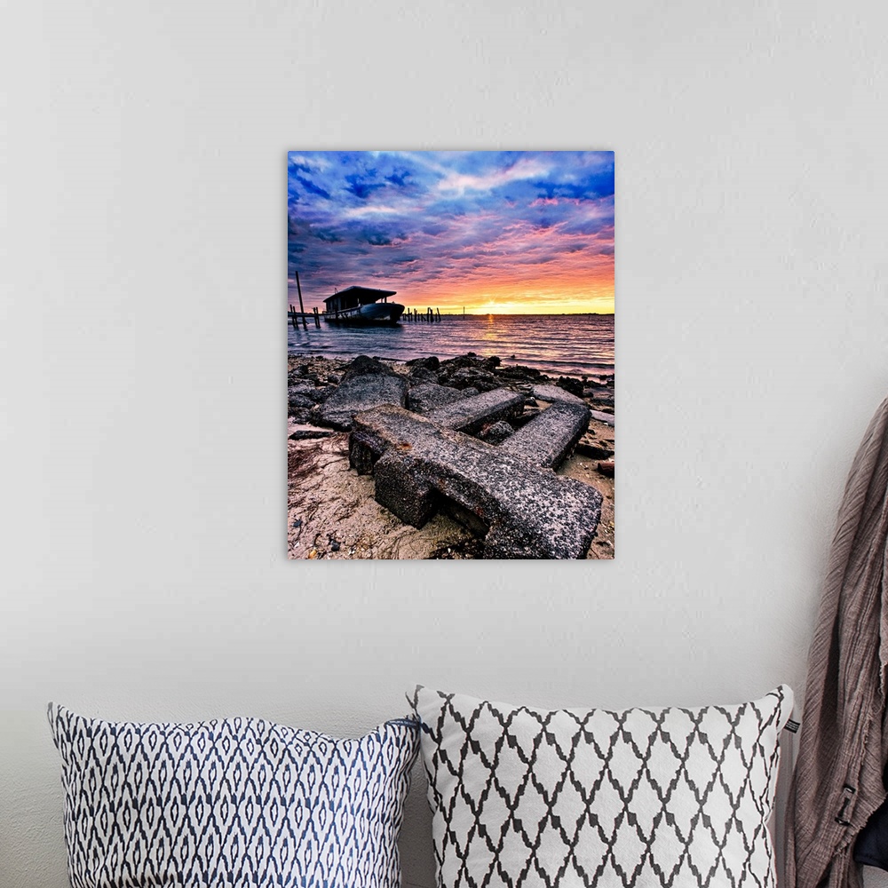 A bohemian room featuring Barnacles cover the shore and an old boat by the sea during sunrise.