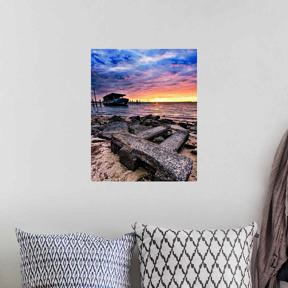A bohemian room featuring Barnacles cover the shore and an old boat by the sea during sunrise.