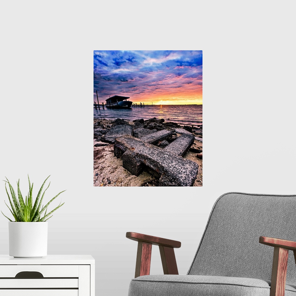 A modern room featuring Barnacles cover the shore and an old boat by the sea during sunrise.