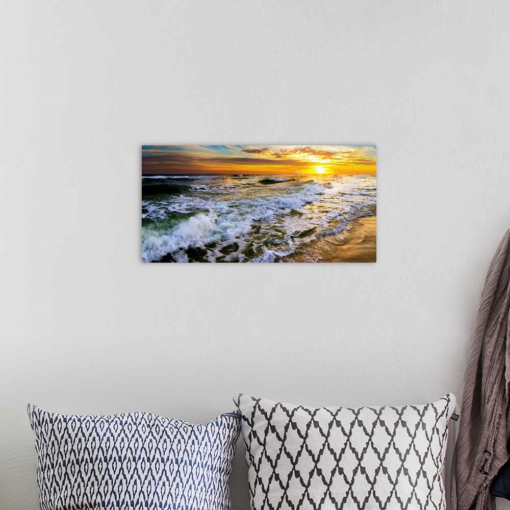 A bohemian room featuring A beautiful ocean sunrise over breaking ocean waves. An art print with waves on the beach with a ...