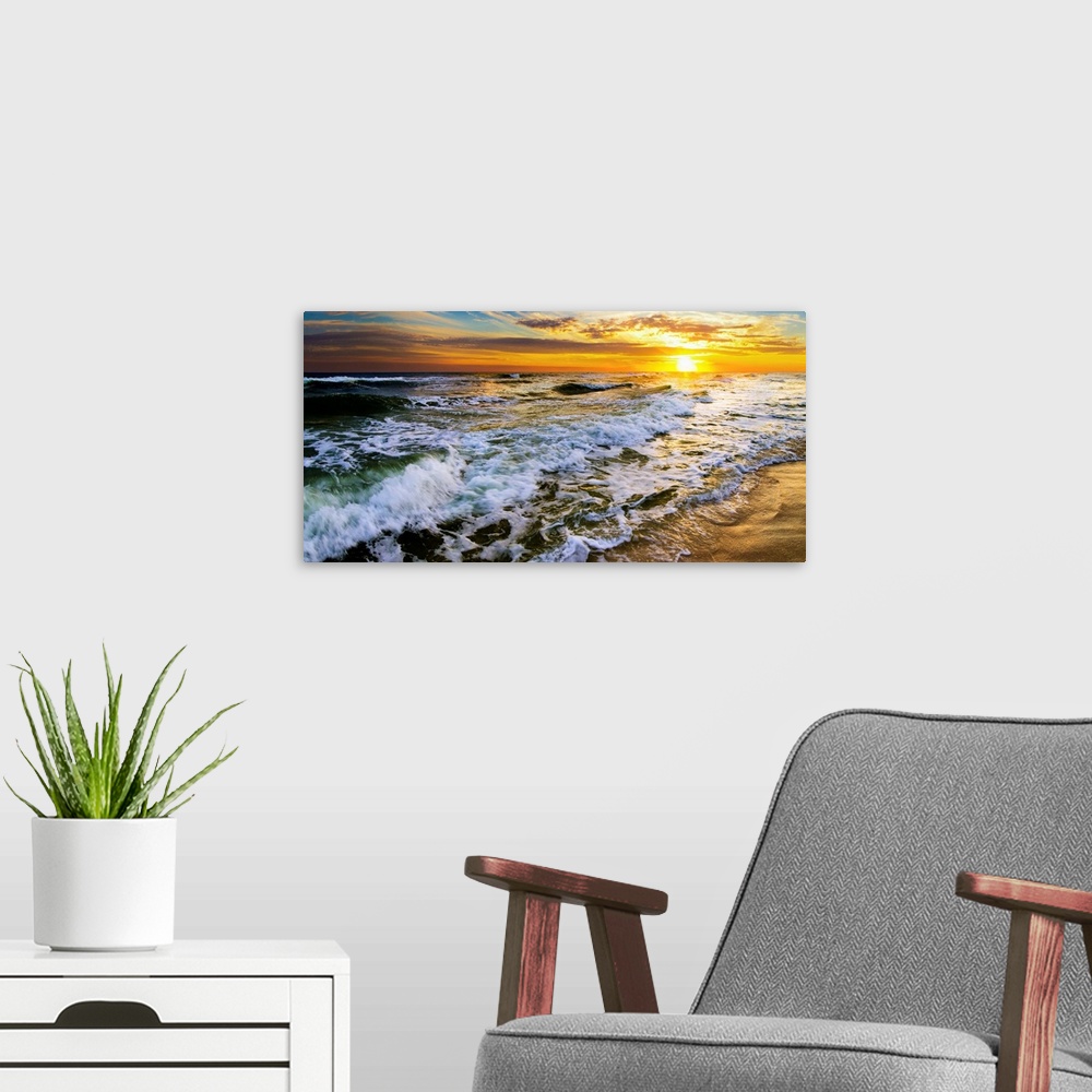 A modern room featuring A beautiful ocean sunrise over breaking ocean waves. An art print with waves on the beach with a ...