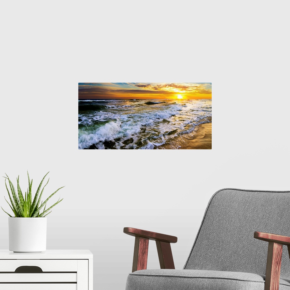 A modern room featuring A beautiful ocean sunrise over breaking ocean waves. An art print with waves on the beach with a ...