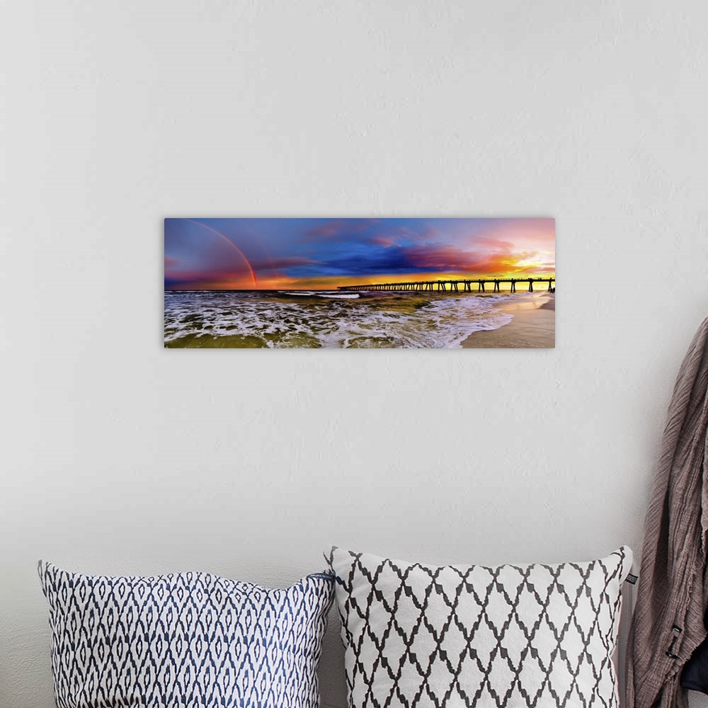 A bohemian room featuring A dark blue sky with a purple sunset featuring a full rainbow. A long pier can be seen reaching i...