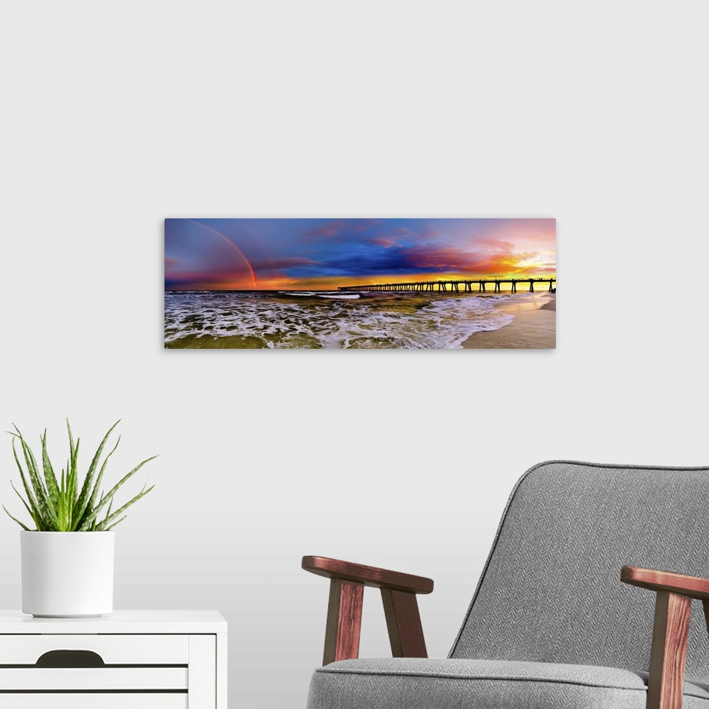 A modern room featuring A dark blue sky with a purple sunset featuring a full rainbow. A long pier can be seen reaching i...