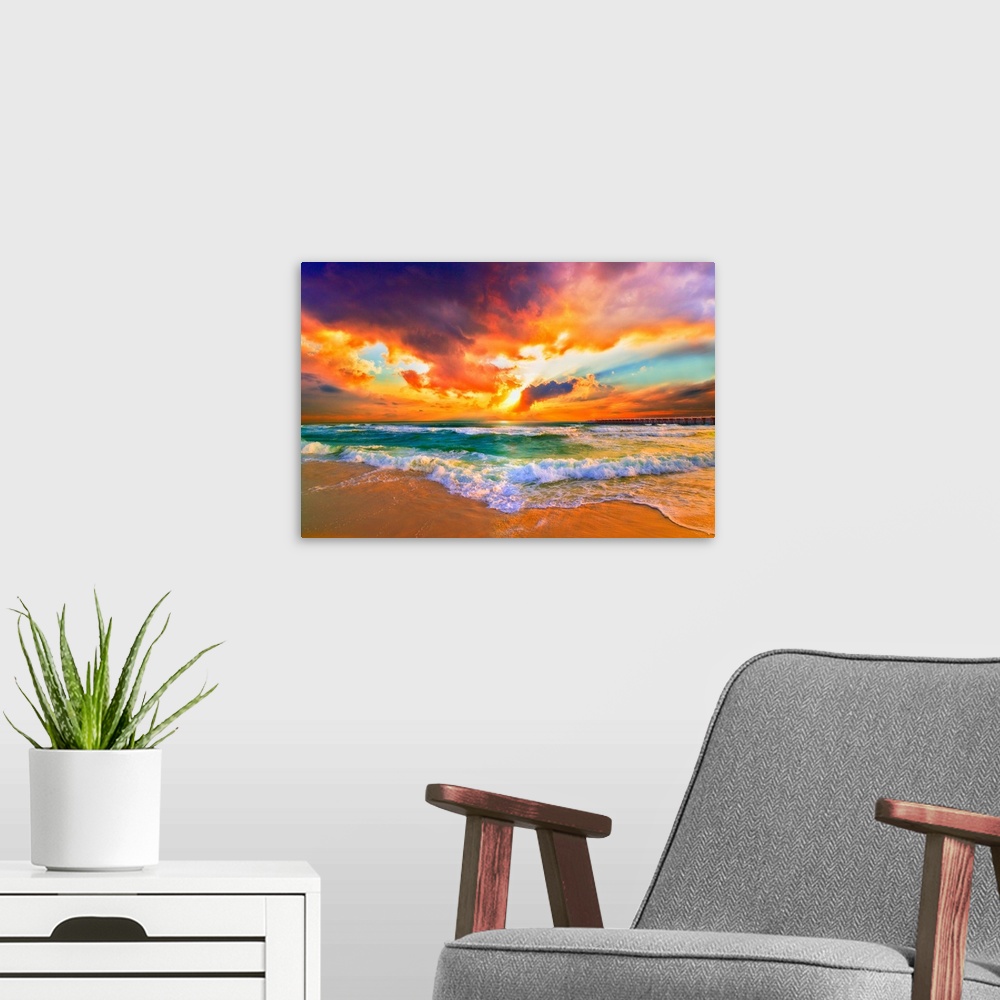A modern room featuring Landscape photography featuring a bright red sunset. Waves crash together in the green sea.