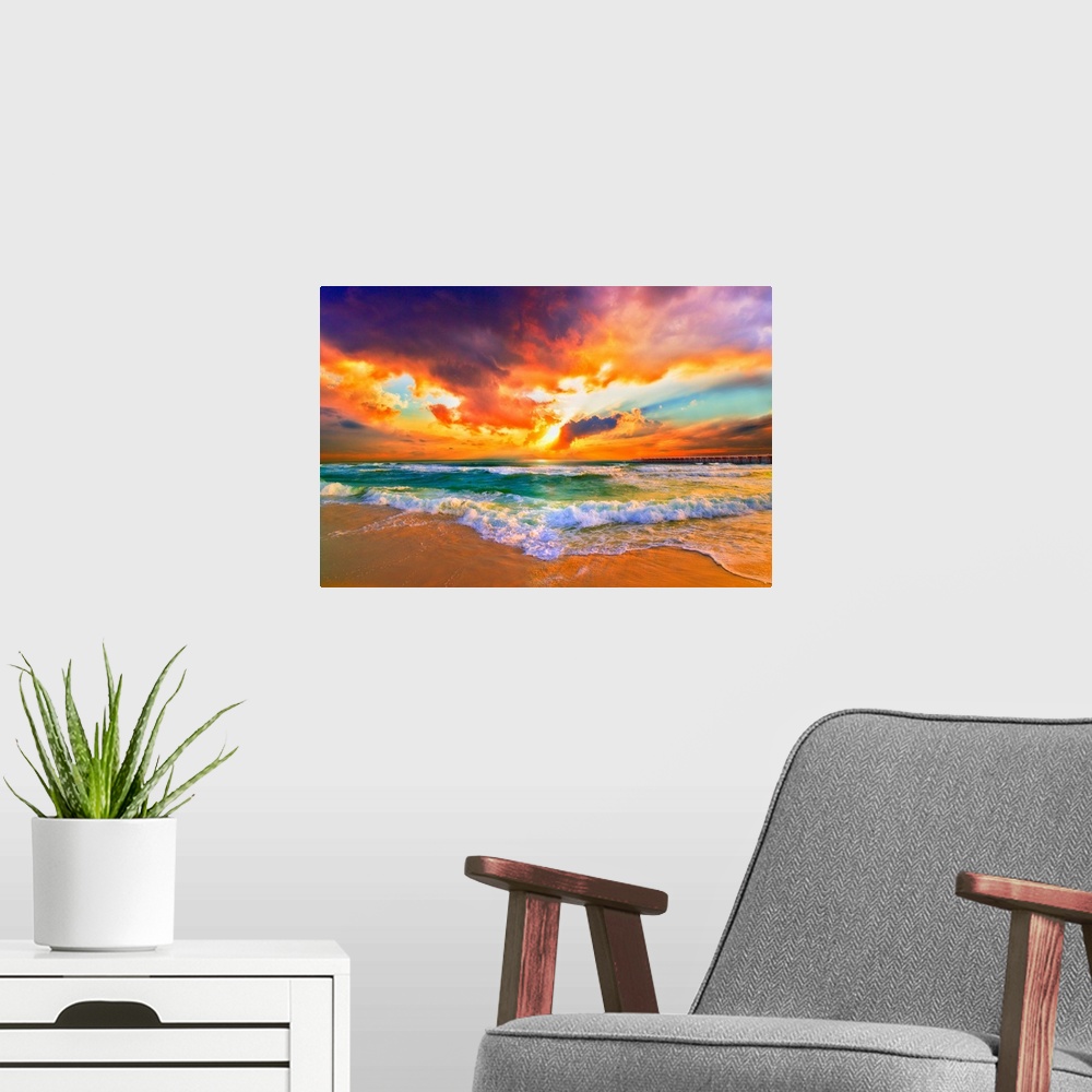 A modern room featuring Landscape photography featuring a bright red sunset. Waves crash together in the green sea.
