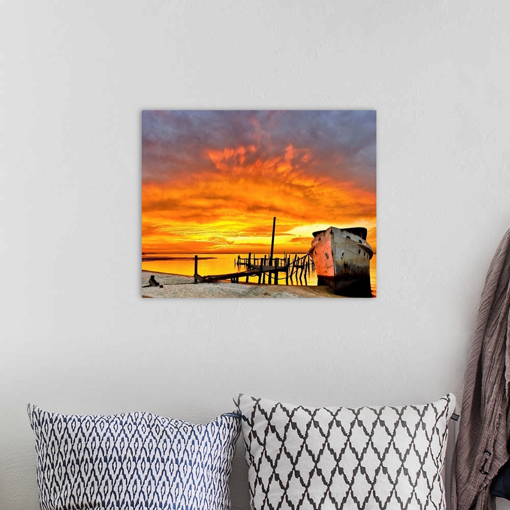 A bohemian room featuring A dark red sunrise behind an old boat and broken pier. Landscape taken near Navarre Beach, Florida.