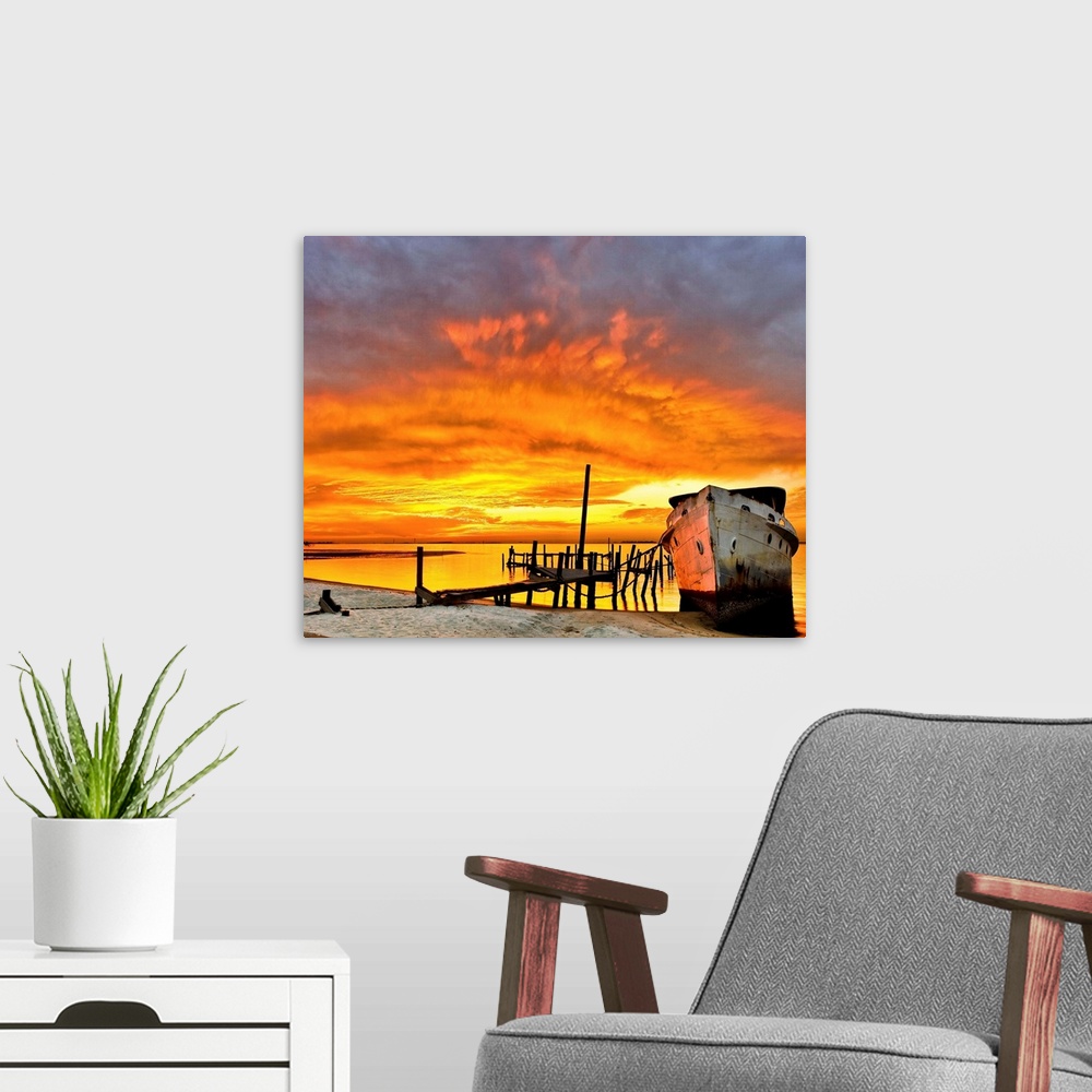 A modern room featuring A dark red sunrise behind an old boat and broken pier. Landscape taken near Navarre Beach, Florida.
