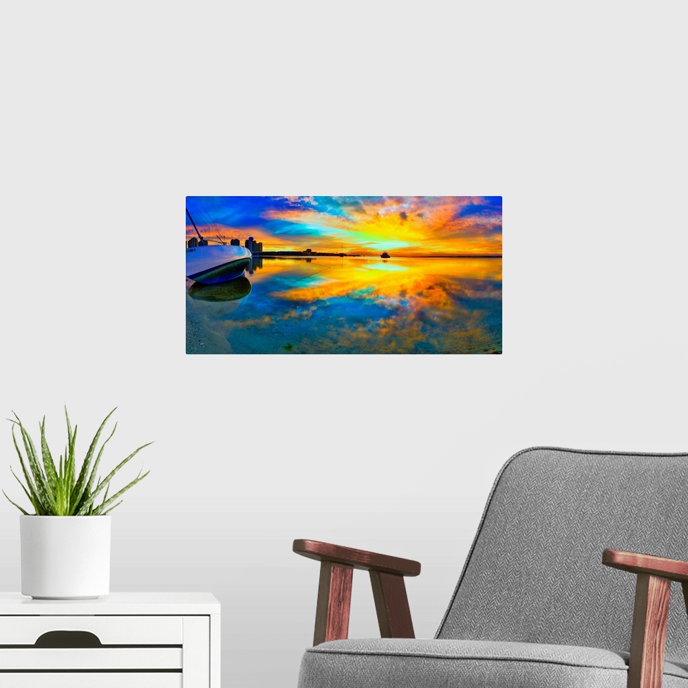 A modern room featuring A panoramic beach sunset with a burning bright reflection in the water. Yellow and blue sky refle...