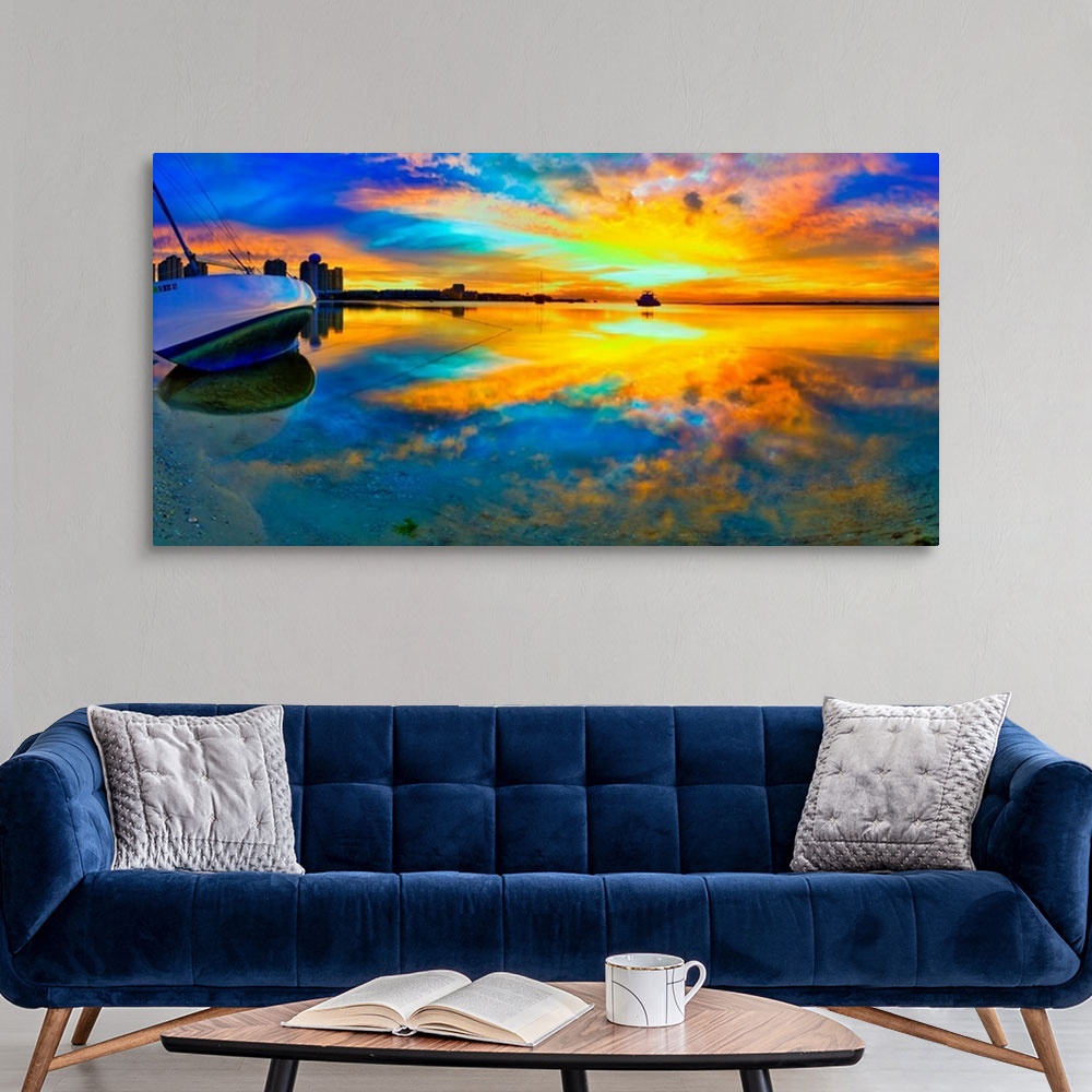 A modern room featuring A panoramic beach sunset with a burning bright reflection in the water. Yellow and blue sky refle...