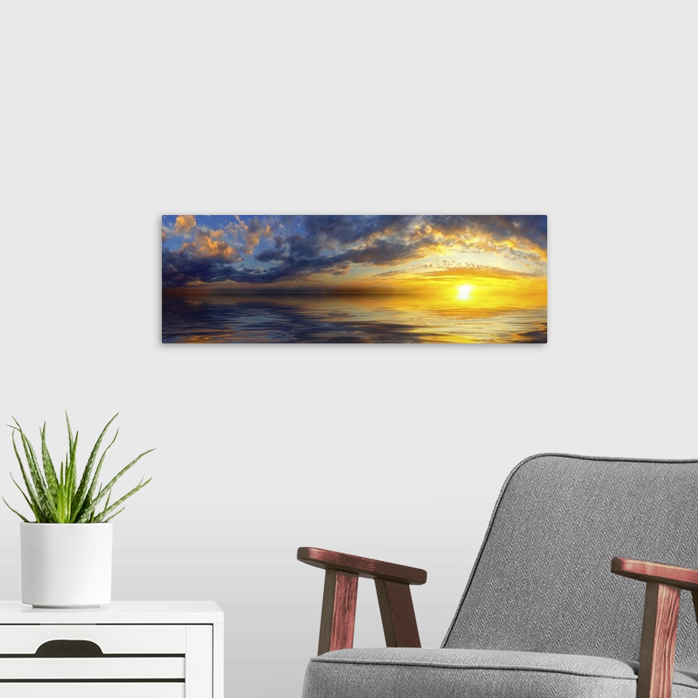 A modern room featuring A beautiful panoramic sunset with bright yellow clouds and a golden cloudscape reflected in the sea.