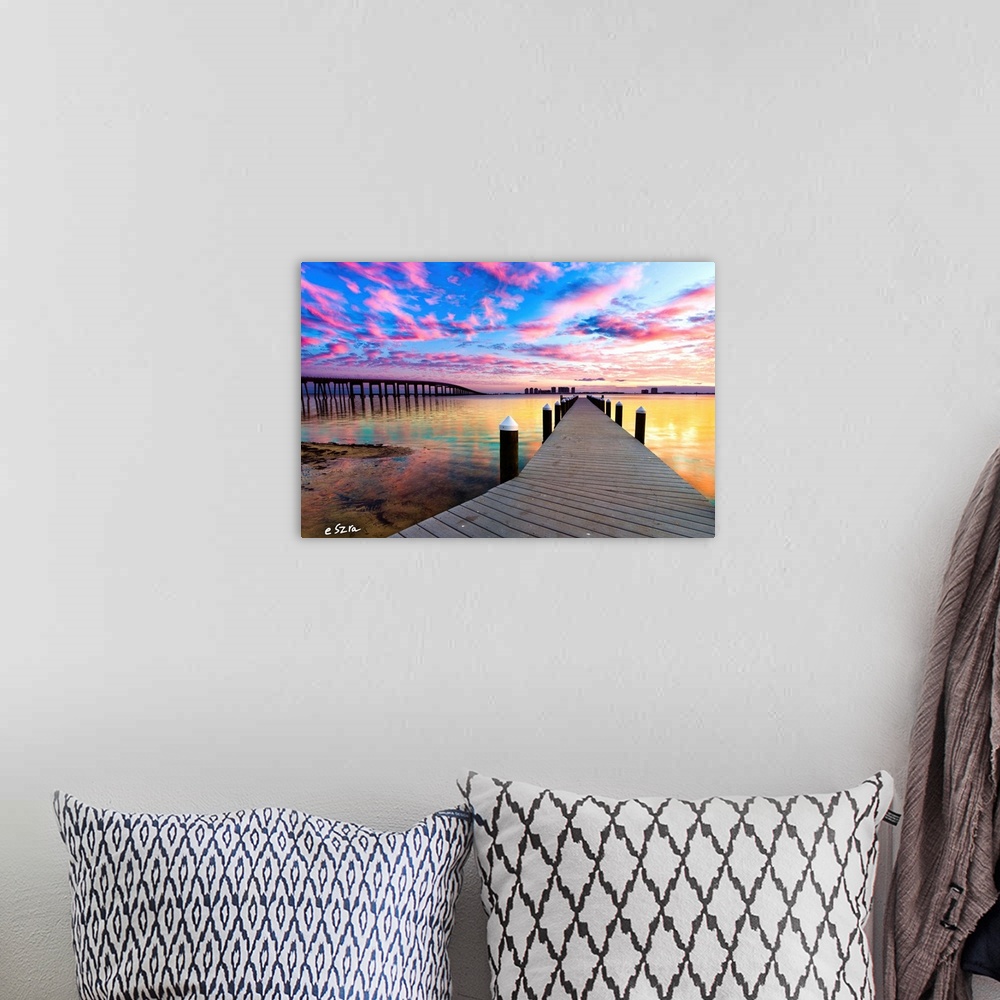 A bohemian room featuring A landscape with a pier under purple clouds near a bridge.