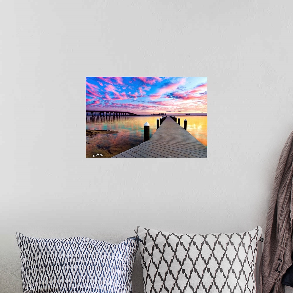 A bohemian room featuring A landscape with a pier under purple clouds near a bridge.