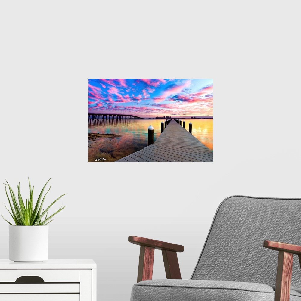 A modern room featuring A landscape with a pier under purple clouds near a bridge.
