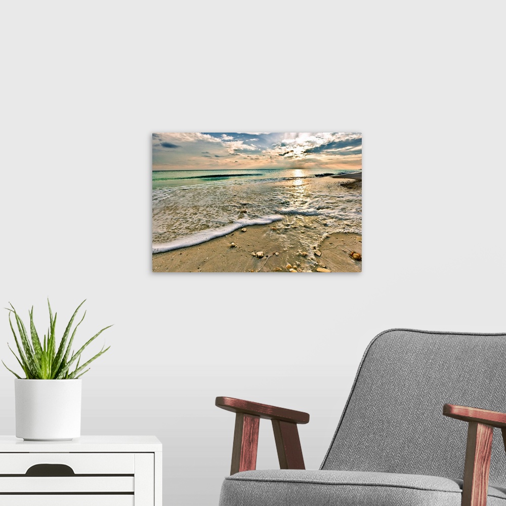 A modern room featuring A sandy shell covered beach and emerald green waves under a bright sunset. A very tranquil and re...