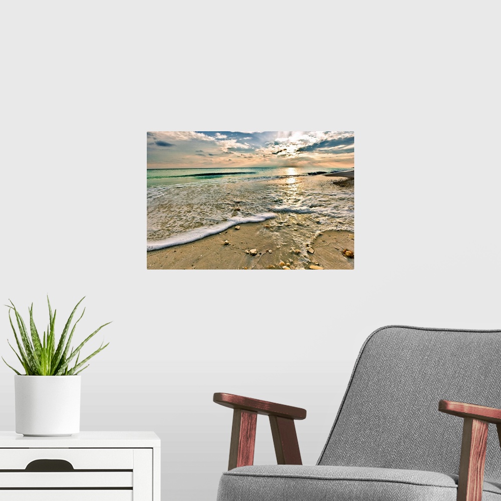 A modern room featuring A sandy shell covered beach and emerald green waves under a bright sunset. A very tranquil and re...