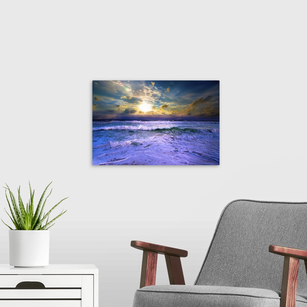 A modern room featuring A bright yellow sunset with blue waves crashing on the beach.