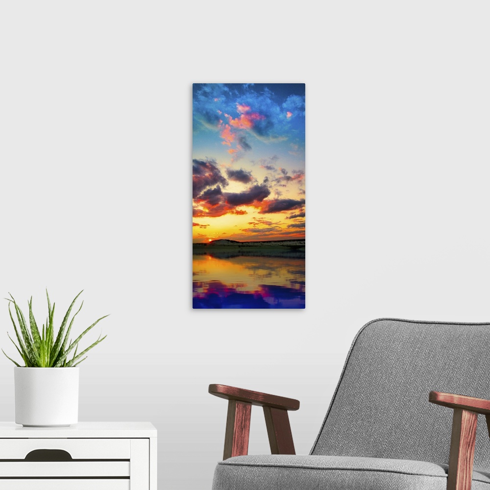 A modern room featuring A tall vertical panorama of a sunset reflection on a lake with red and purple clouds.