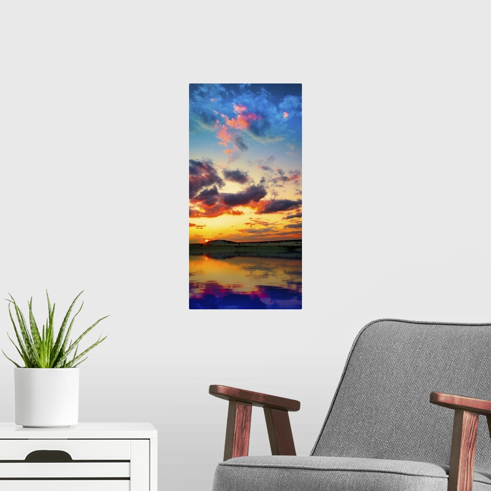 A modern room featuring A tall vertical panorama of a sunset reflection on a lake with red and purple clouds.