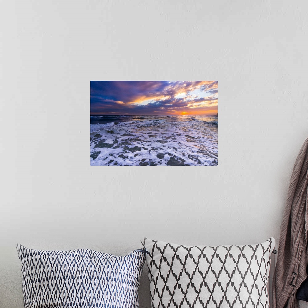 A bohemian room featuring Breaking white waves in this seascape under an orange sunset.