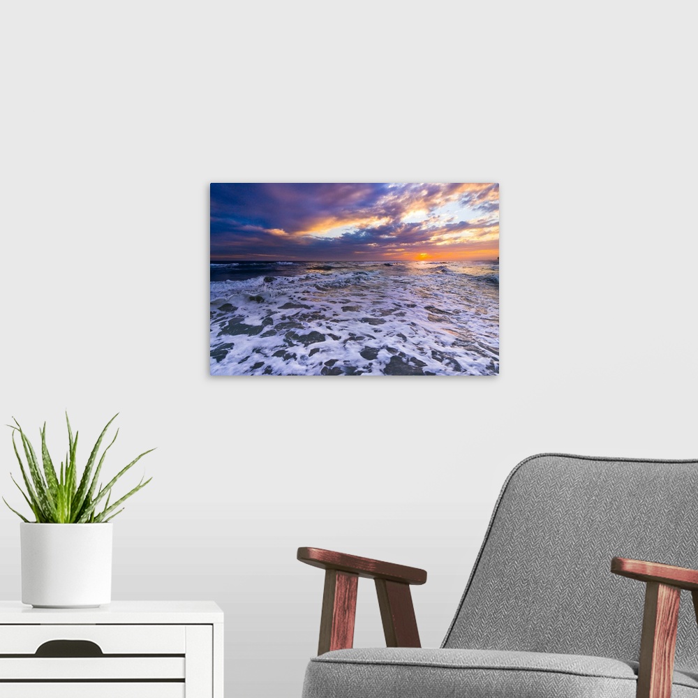 A modern room featuring Breaking white waves in this seascape under an orange sunset.