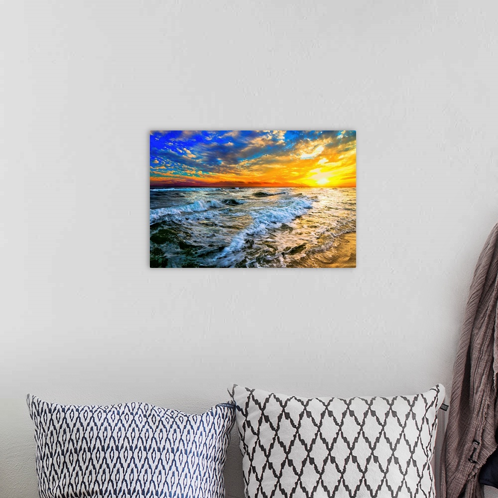 A bohemian room featuring Beautiful ocean waves roll in front of a yellow orange and blue sunset. The sunset goes down into...