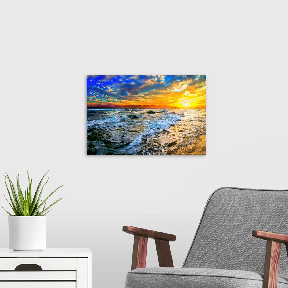 A modern room featuring Beautiful ocean waves roll in front of a yellow orange and blue sunset. The sunset goes down into...