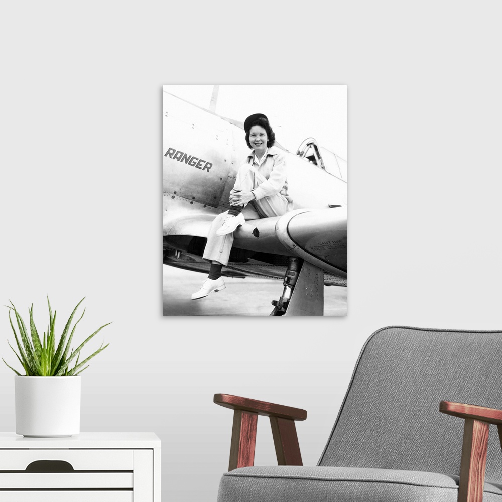 A modern room featuring Margaret (Mickey) McGrath, former WASP sitting on the wing of in an XAT-6E trainer aircraft. It w...