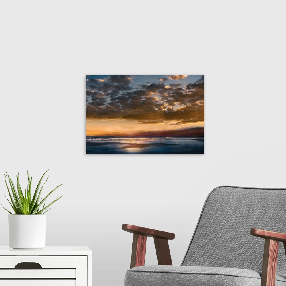 A modern room featuring Seascape photograph with mountains in the distance and a cloudy sky at sunset.