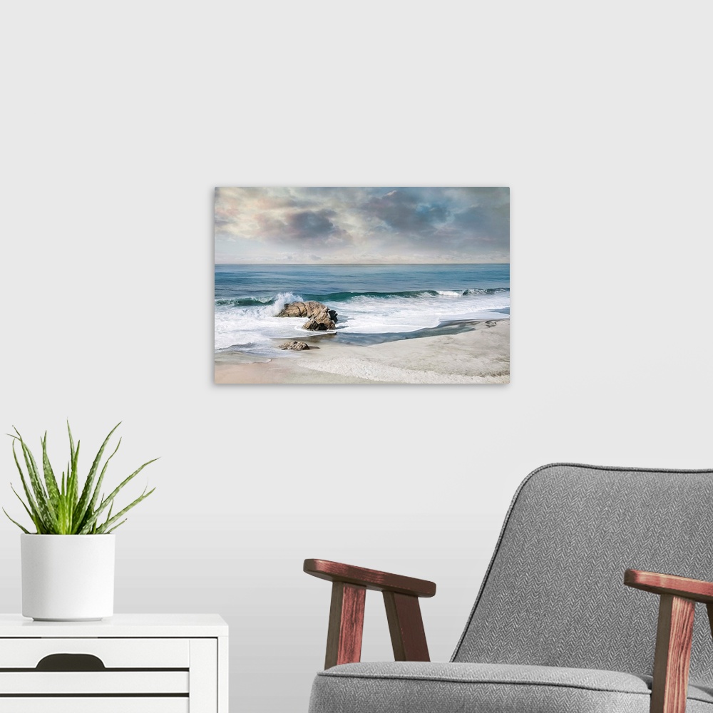 A modern room featuring Landscape photograph of waves crashing onto a rock on the sandy shore.