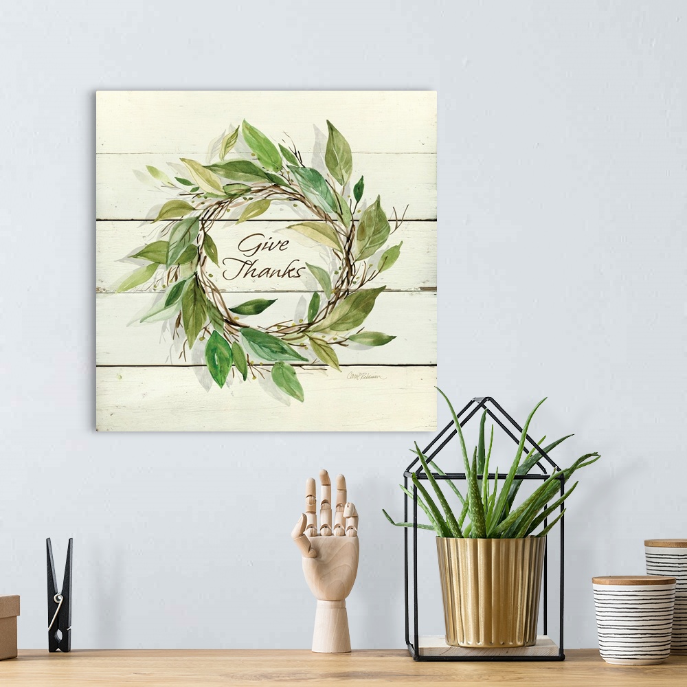 A bohemian room featuring Decroative artwork of a wreath of leaves with the text "Give Thanks" in the middle on a white woo...