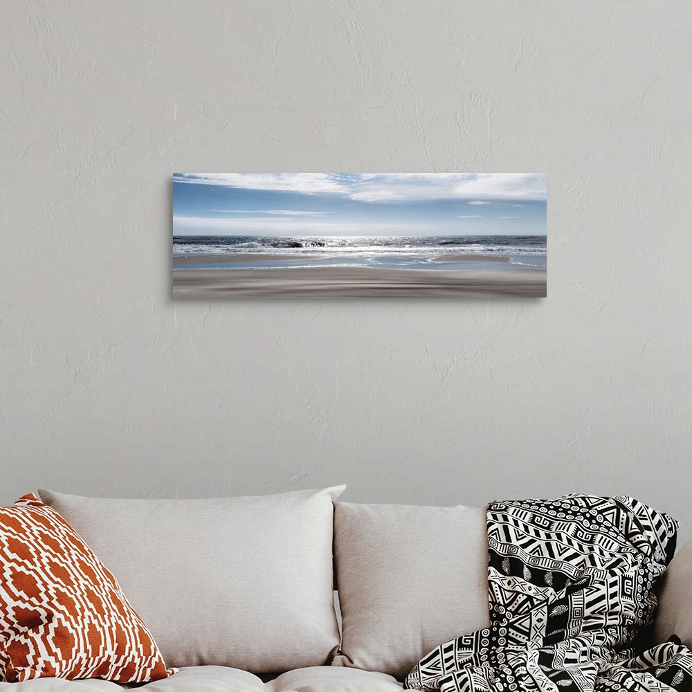 A bohemian room featuring A panoramic photo illustrating a tranquil view of the beach as the sun shimmers on the sea.