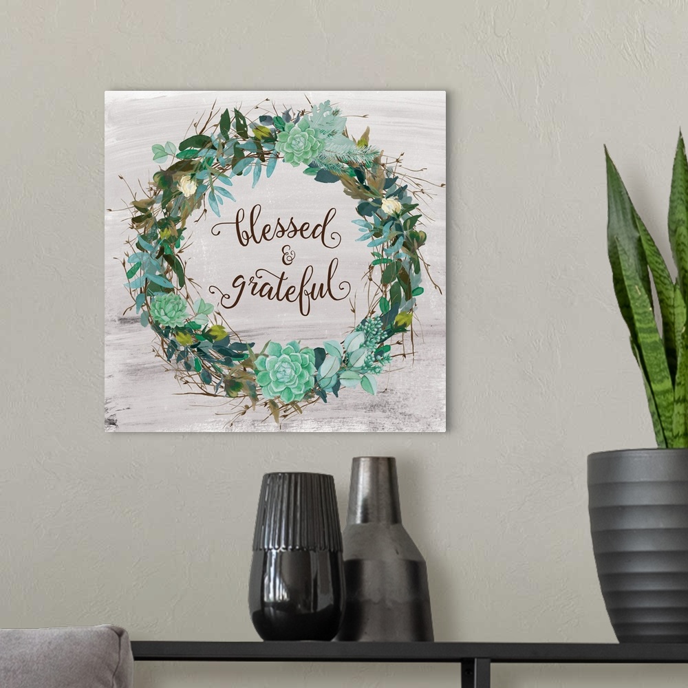 A modern room featuring "Blessed and Grateful" written inside a wreath made of greenery and succulents with a few small f...