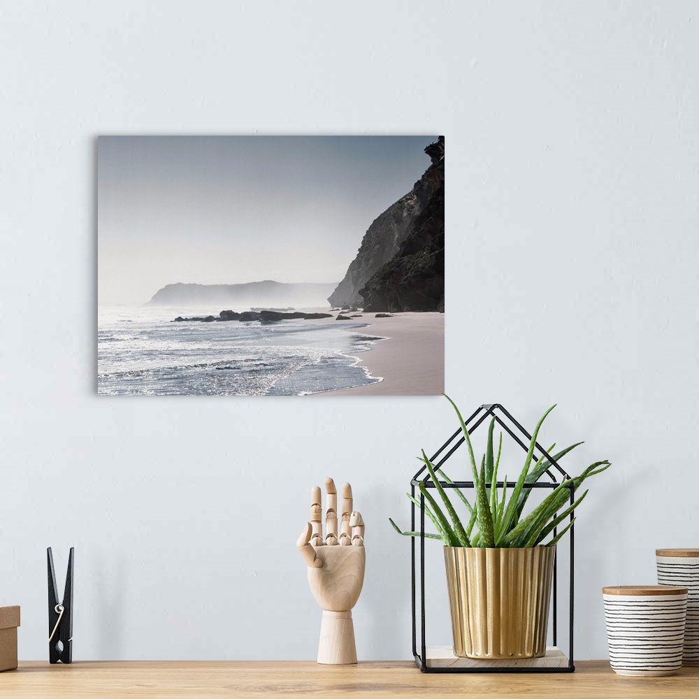 A bohemian room featuring Cool toned photograph of a misty shore with giant rock cliffs.