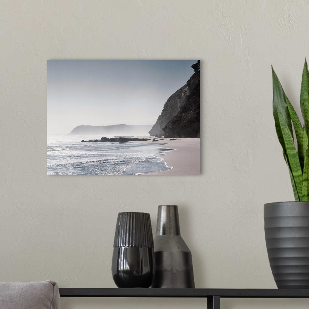 A modern room featuring Cool toned photograph of a misty shore with giant rock cliffs.