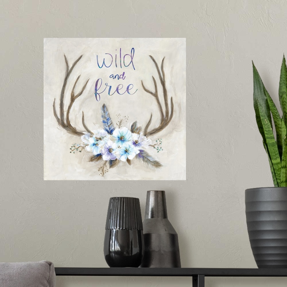 A modern room featuring Square painting of antlers decorated with flowers and feathers and has the phrase "Wild and Free"...