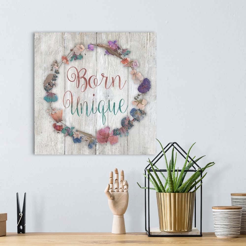 A bohemian room featuring "Born Unique" placed on a white washed wood texture with dried flowers surrounding it.