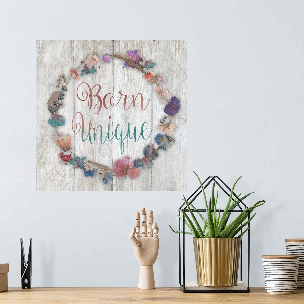 A bohemian room featuring "Born Unique" placed on a white washed wood texture with dried flowers surrounding it.