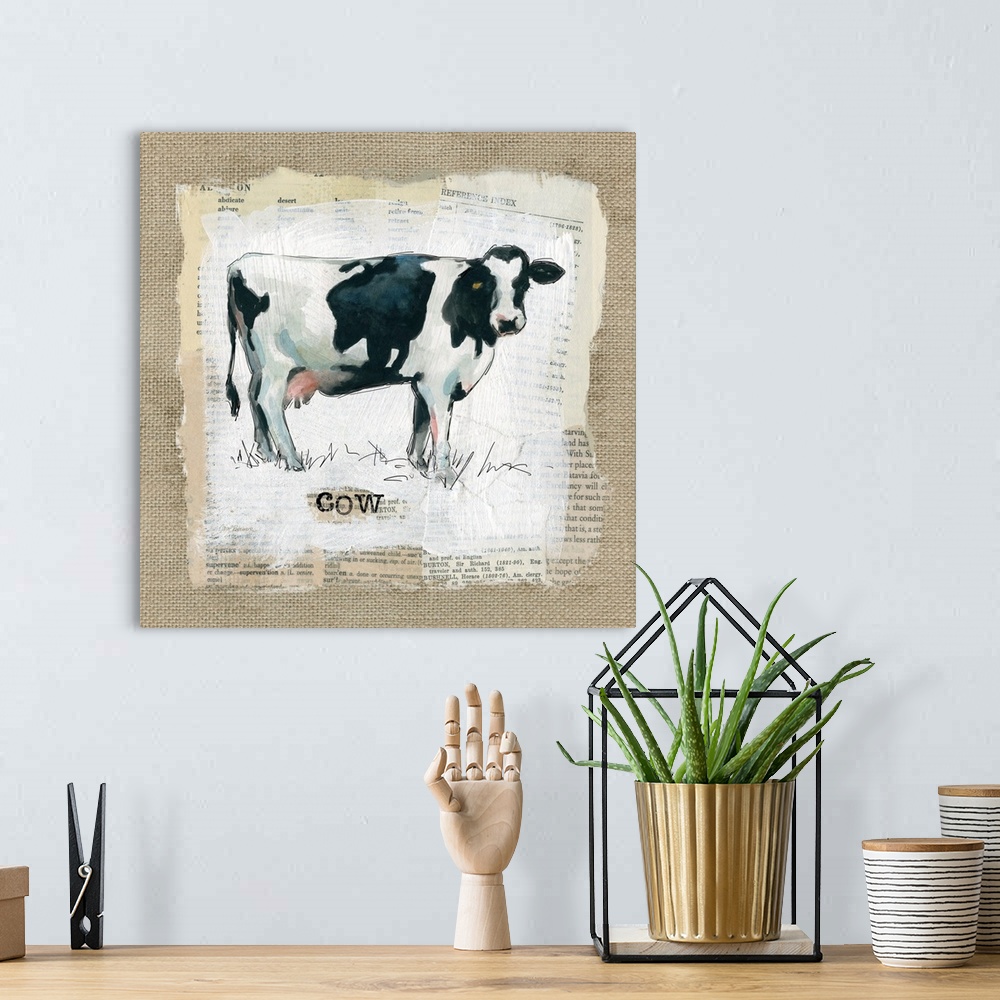 A bohemian room featuring Square burlap collage art of a cow painted on top of newspaper clippings with the word "cow" stam...