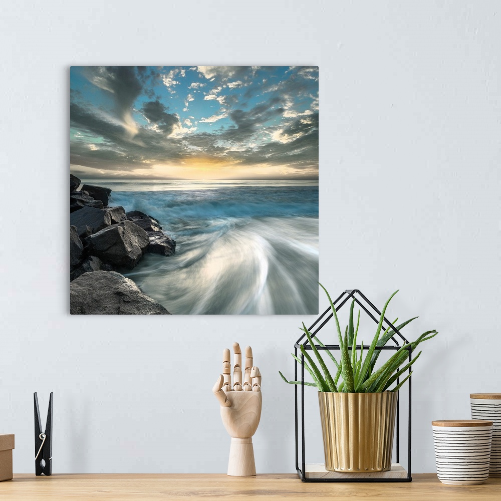 A bohemian room featuring Long exposure photograph of ocean waves crashing on a rocky beach shore with a dramatic sky.