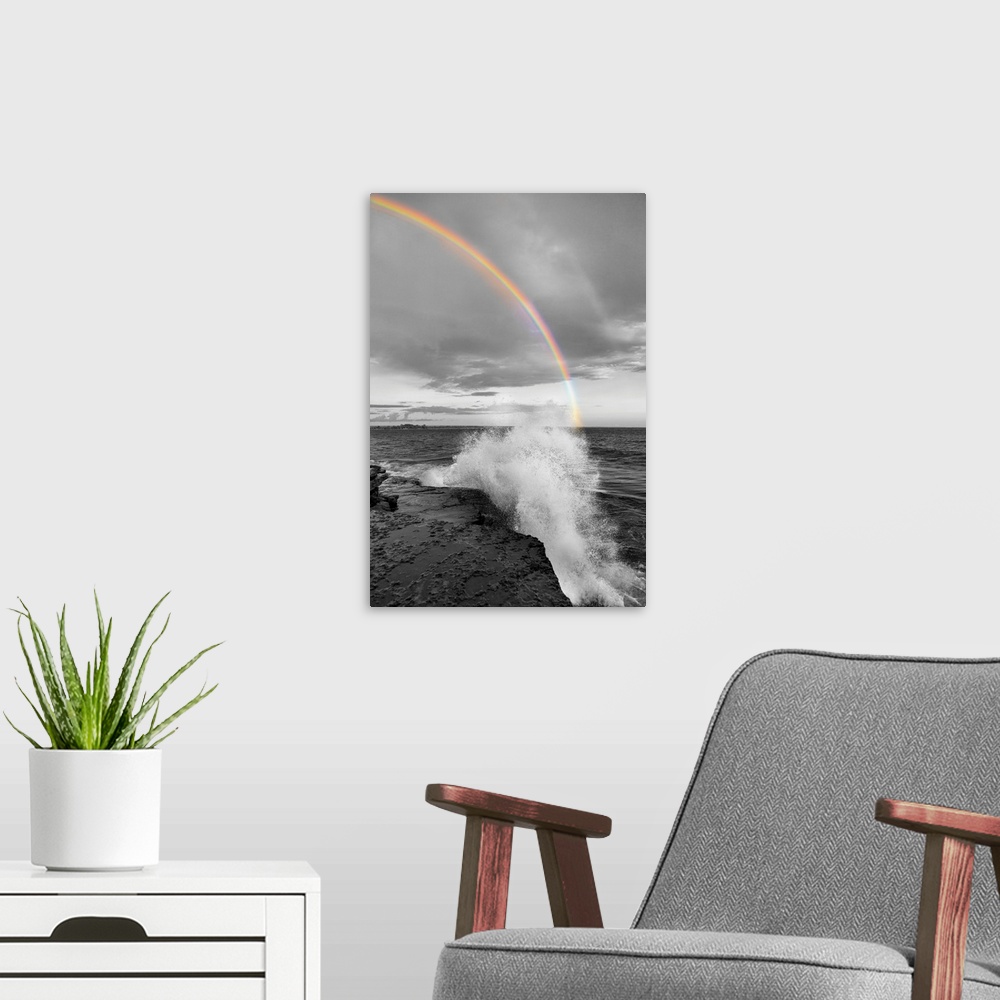 A modern room featuring Black and white photograph of a waves crashing on a rocky shore with a colorful rainbow over the ...
