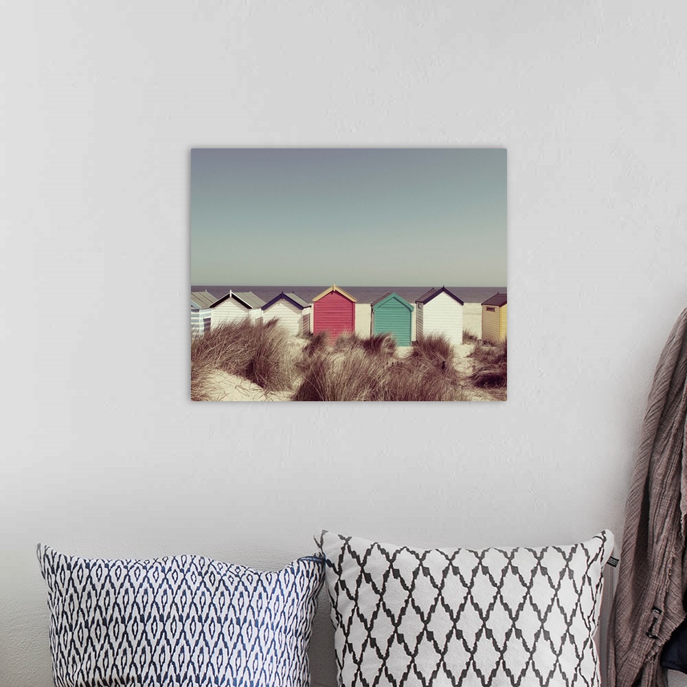 A bohemian room featuring A photograph of multi-colored cottages lined up in a row on the beach.