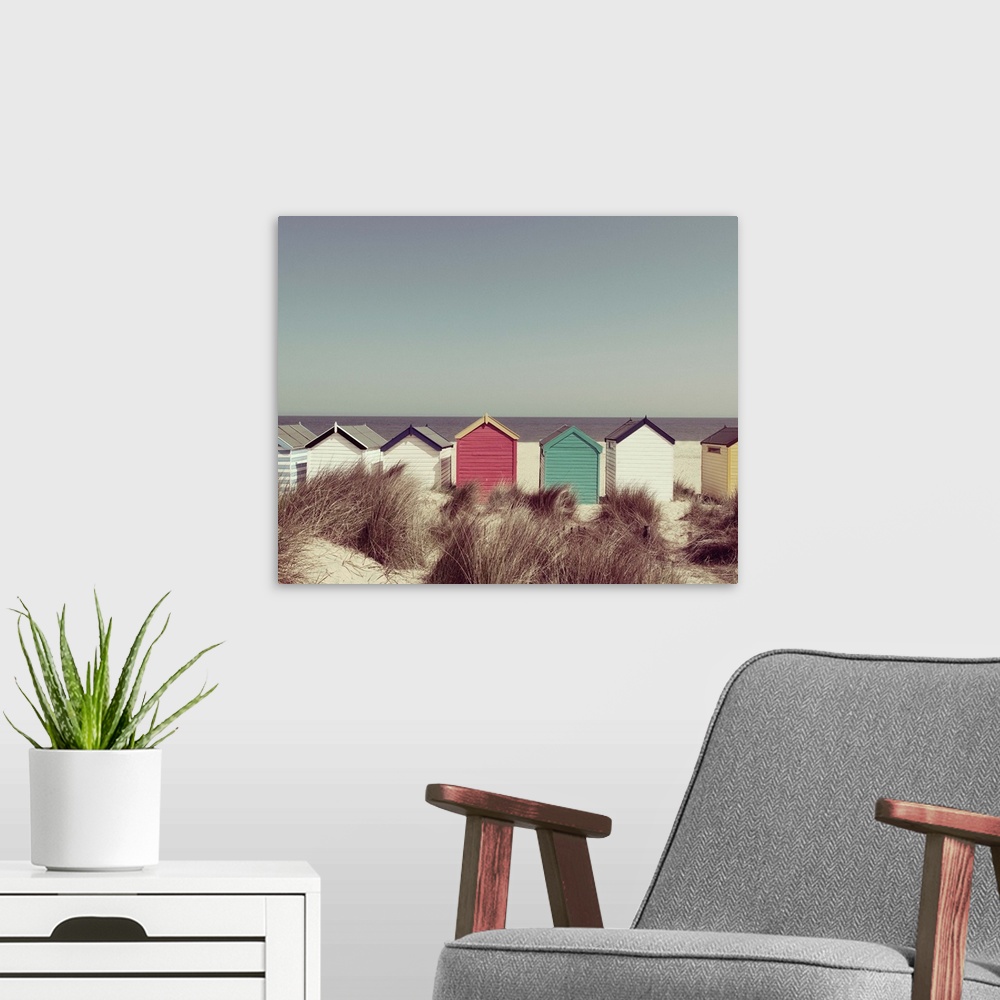 A modern room featuring A photograph of multi-colored cottages lined up in a row on the beach.