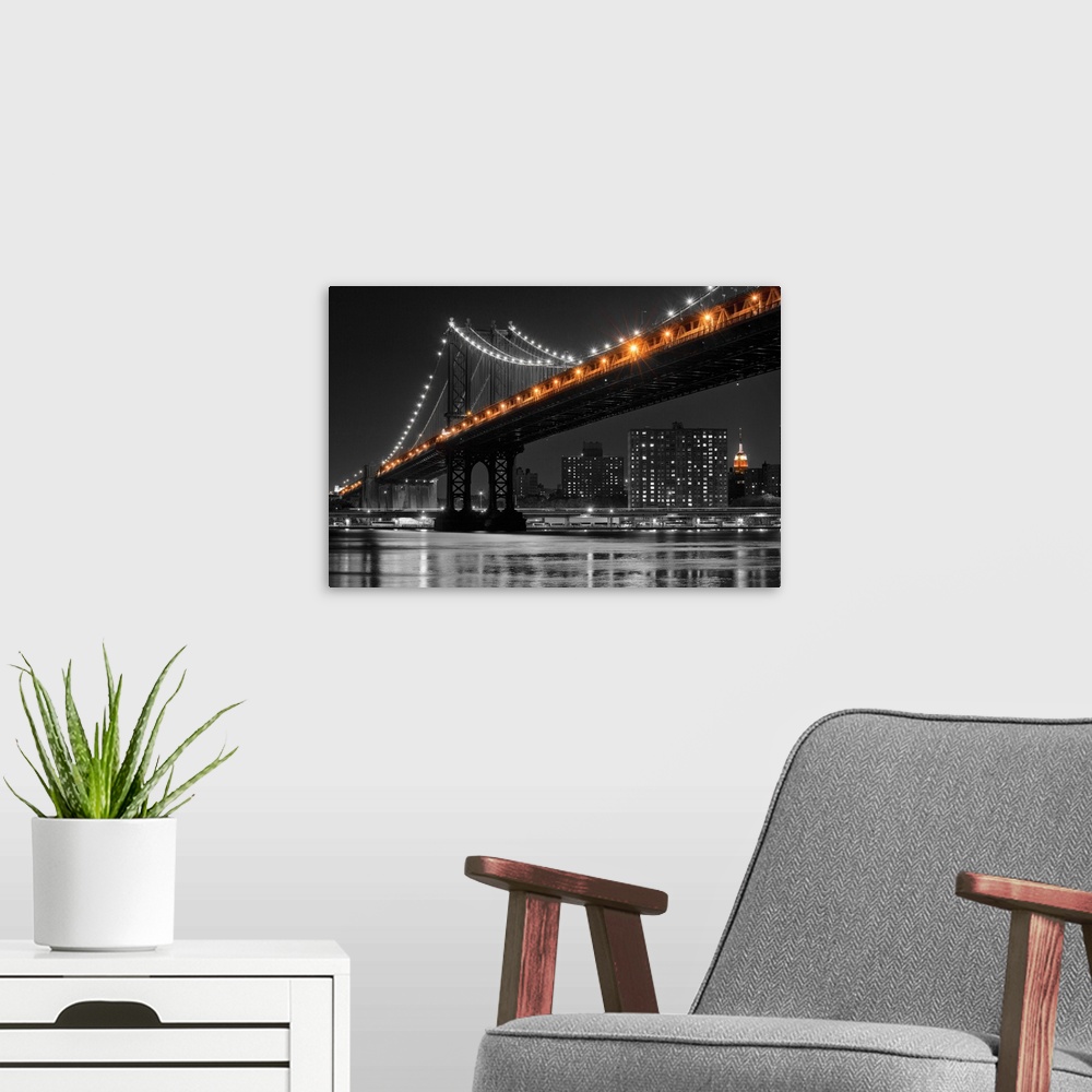 A modern room featuring Black and white photograph of the Manhattan Bridge at night with only the lights in color.